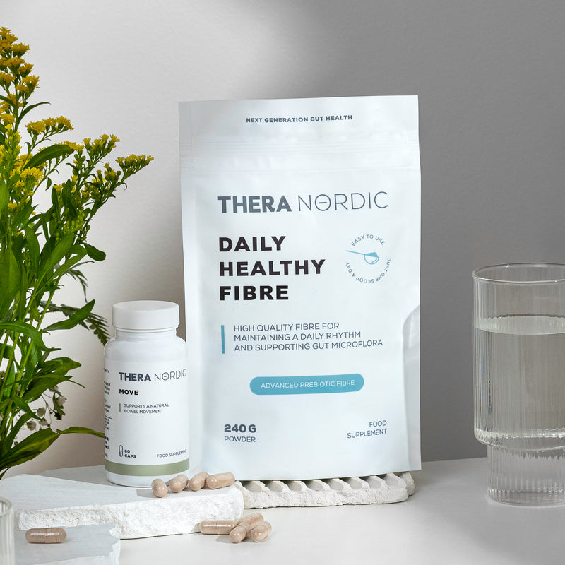 Thera Nordic dietary supplements and a glass of water on a table with green plants.