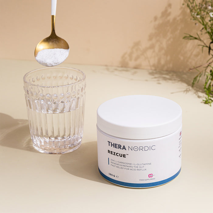 Thera Nordic REZCUE supplement beside a glass of water and spoonful of powder.
